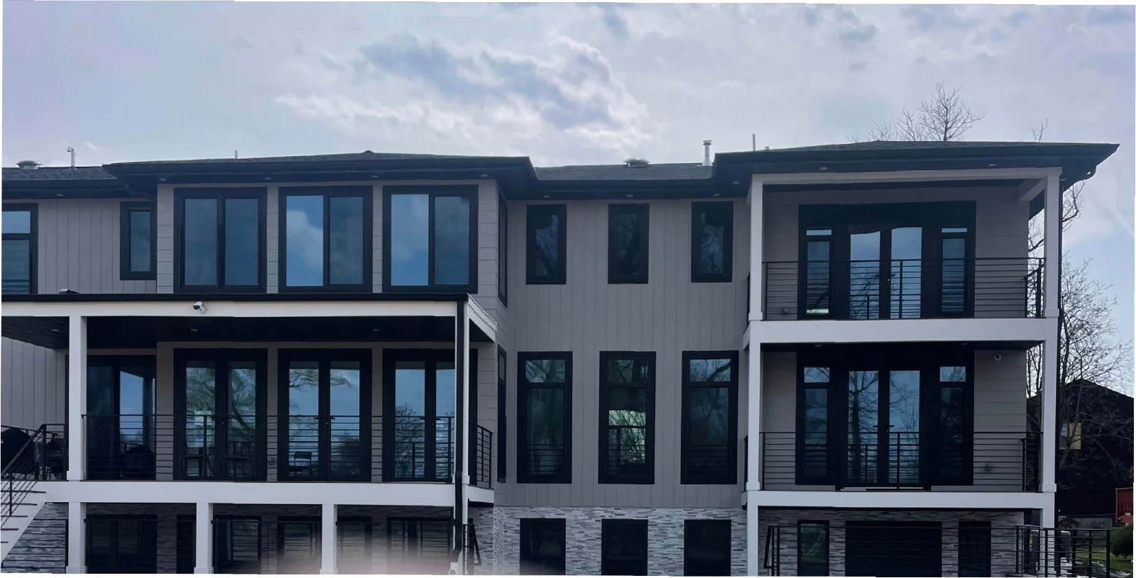 Luxury Paramus residence by JD Homes with multi-level decks, black railings, and stone foundation